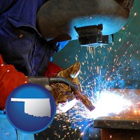 oklahoma an industrial welder wearing a welding helmet and safety gloves