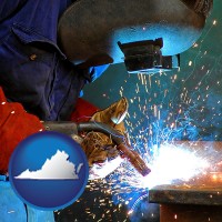 virginia an industrial welder wearing a welding helmet and safety gloves