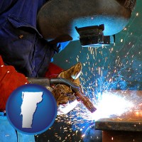 vermont an industrial welder wearing a welding helmet and safety gloves