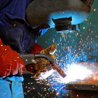 an industrial welder wearing a welding helmet and safety gloves