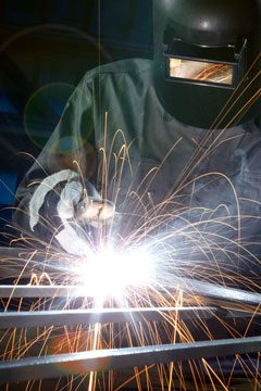 a welder welding a steel frame while wearing a safety visor
