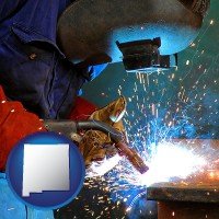 new-mexico an industrial welder wearing a welding helmet and safety gloves